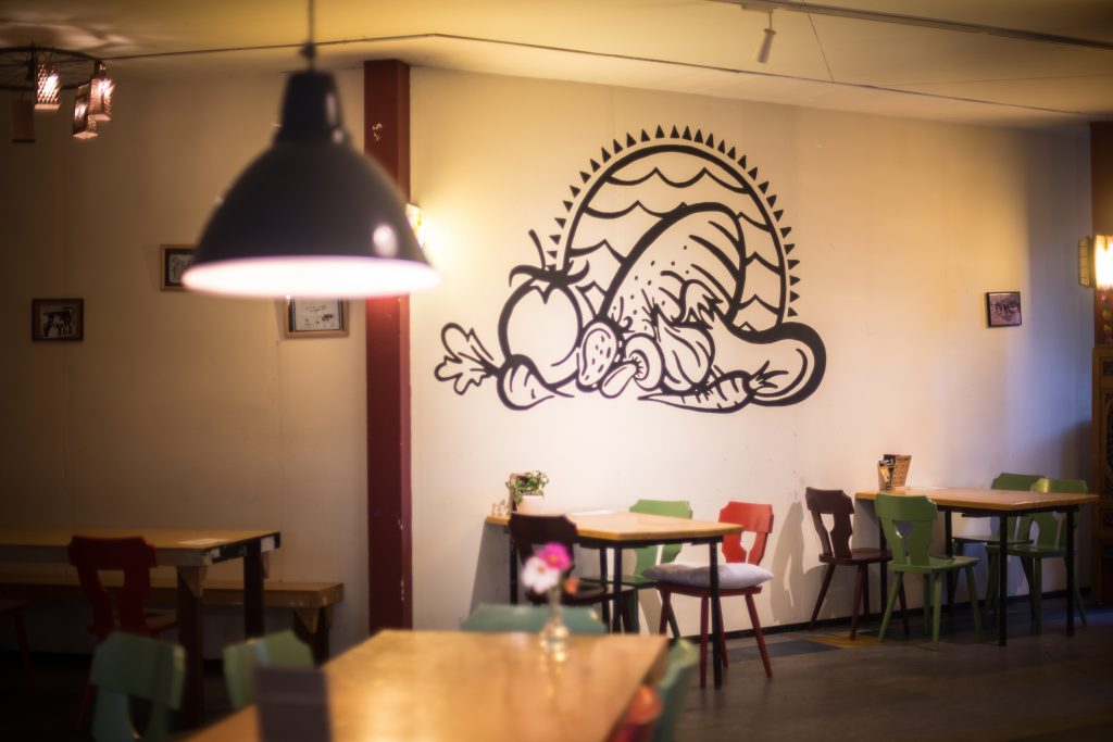 The inside of the Eetcafe Water en brood, with the logo of veggies and bread and water, painted on the wall, in the middle